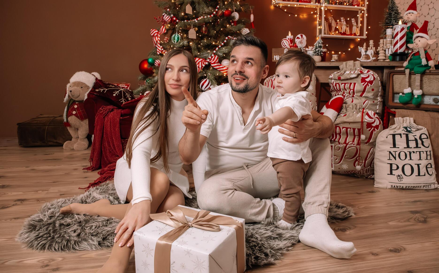 Család fotózása karácsonyi dekoráció közt gyermekükkel az ölükben