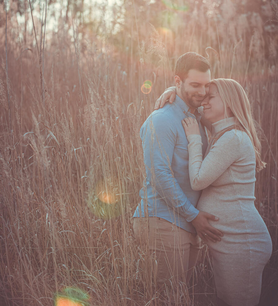 Kismama és apa fotózása a természetben a lemenő nap fényében a háttérben