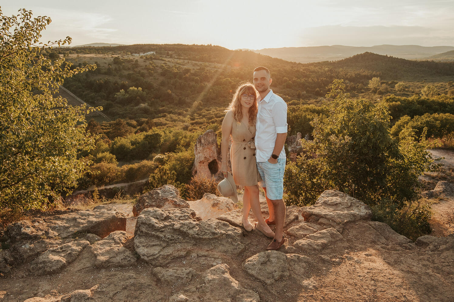 Szerelmes pár a Teve szikla szélén áll a naplementében